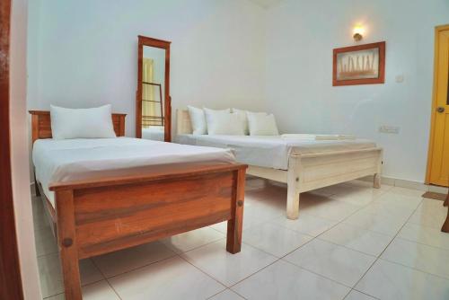 a bedroom with two beds and a mirror at TENBY Guest House in Anuradhapura