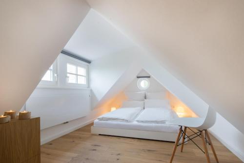 a bedroom with a white bed and a chair at Lütthüs Blankenese in Hamburg