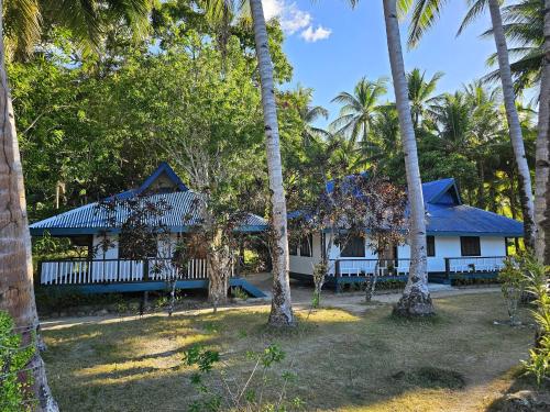 a house with palm trees in front of it at DK2 Resort - Remote Beach Hideaway - Fast WiFi - Private Tours by Arrangement - Plan Ahead in El Nido