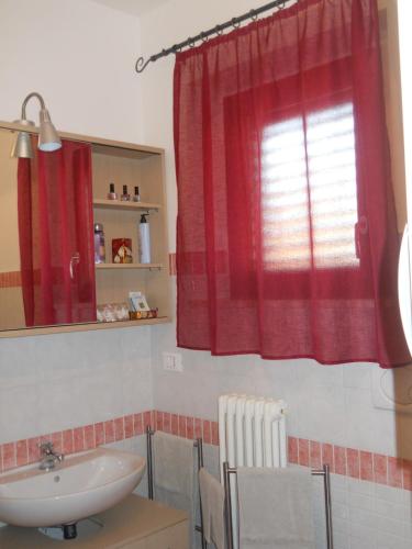 a bathroom with a sink and a red curtain at Sirolo Summer Appartamento in Sirolo