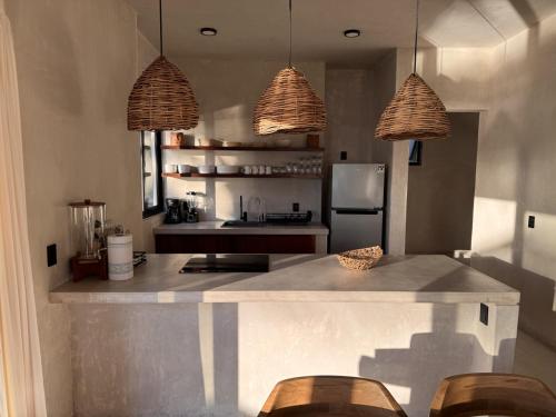 a kitchen with a counter with chairs and two pendant lights at Aldea Cayaco Villa A1 in La Manzanilla
