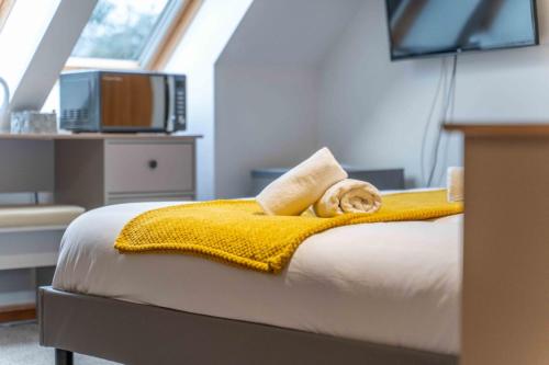 a cat laying on a bed with a yellow blanket at Ben View Room 3 in Fort William