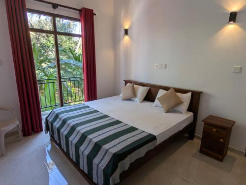 a bedroom with a bed with a large window at The Aurora in Ahangama
