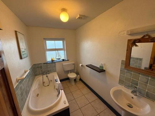 a bathroom with a tub and a sink and a toilet at Portmagee Seaside Cottages - Gannet in Portmagee