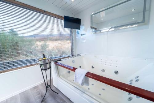 a white bathroom with a tub and a window at Ben View Pod and Jacuzzi Bath in Fort William