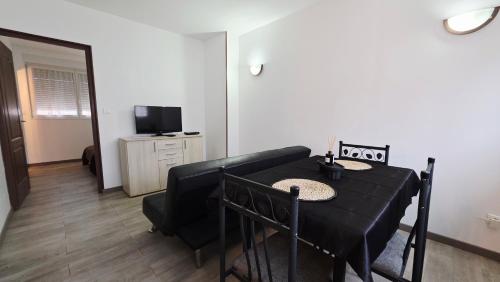 una sala da pranzo con un tavolo nero e una televisione di Studio Foch 3 a Grand-Fort-Philippe