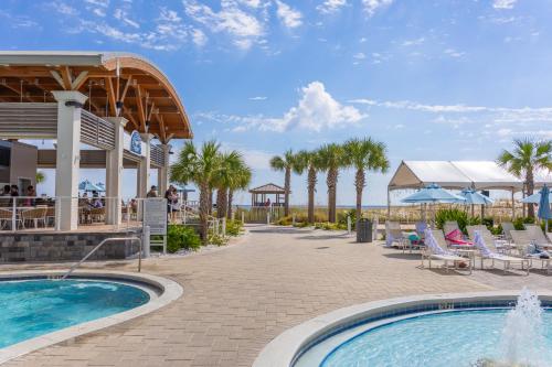 a resort with a swimming pool and palm trees at Hilton Pensacola Beach in Pensacola Beach
