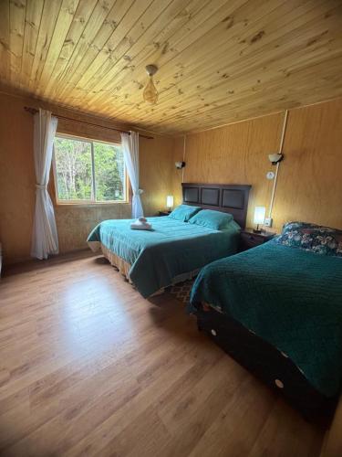 a bedroom with two beds and a wooden ceiling at Cabaña A & M in Chaitén