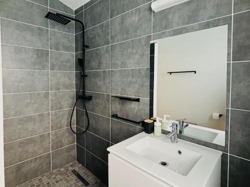 a bathroom with a sink and a shower with a mirror at O coeur de l'ouest Bungalow Maloya in Le Bois de Nèfles