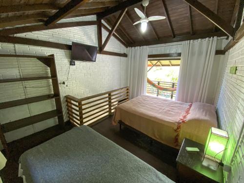 a bedroom with two beds and a window at Pousada Vale da Praia in Praia do Rosa