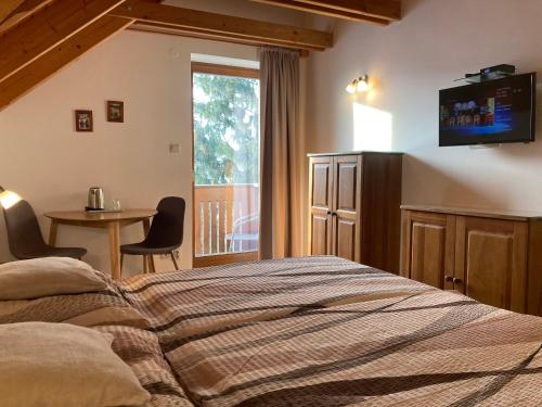 a bedroom with a bed and a table and a window at Penzion Úsmev in Arnutovce