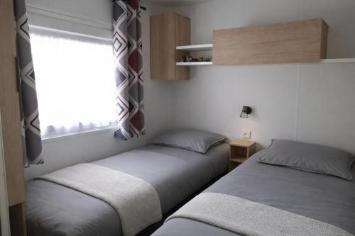Twee bedden in een kleine kamer met een raam. bij Chez Achille in Marcilly-sur-Eure
