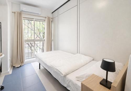 a white bedroom with a bed and a window at Alicante Beach Hostel in Alicante