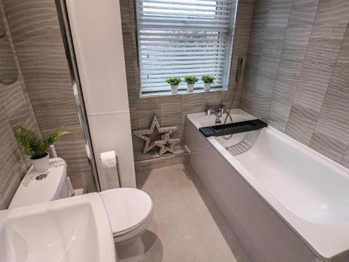 a bathroom with a toilet and a tub and a sink at Eleven Tides in Seaham