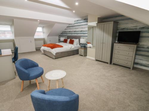 a bedroom with a bed and two chairs and a tv at Eleven Tides in Seaham