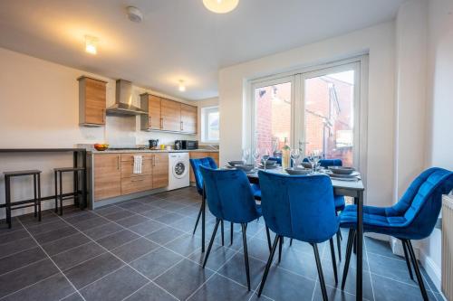 a kitchen and dining room with a table and blue chairs at Atlanta's Residence by Tŷ SA in Newport