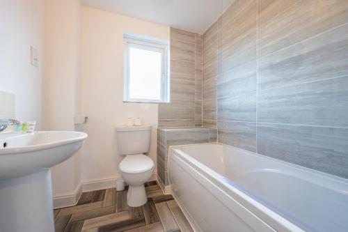 a bathroom with a toilet and a tub and a sink at Atlanta's Residence by Tŷ SA in Newport