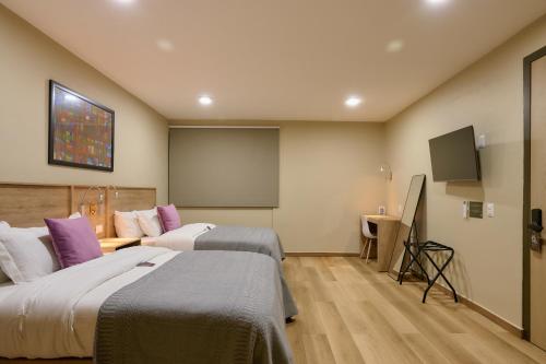 a hotel room with two beds and a flat screen tv at Suites el Consuelo in Oaxaca City
