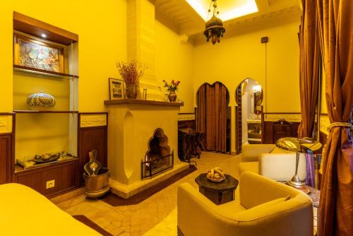 a living room with yellow walls and a fireplace at Riad Habouba in Marrakesh