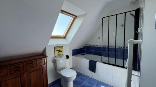 a bathroom with a toilet and a tub and a window at Maison des Dunes in Plougoulm