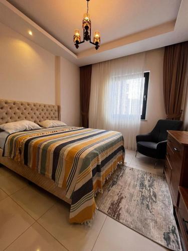 a bedroom with a bed and a chair and a window at Serenity Residence apartment in Alanya