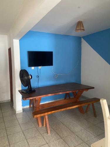 a wooden table with a tv on a blue wall at Luar Dos Milagres in São Miguel dos Milagres
