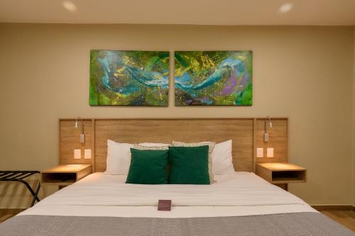 a bedroom with a bed with two paintings on the wall at Suites el Consuelo in Oaxaca City
