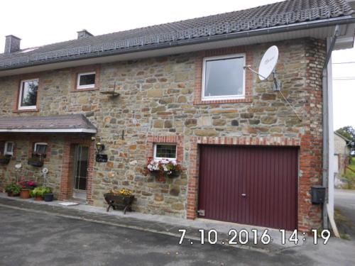 ein Backsteinhaus mit einer roten Garage in der Unterkunft The Cottage and The Loft in Amel