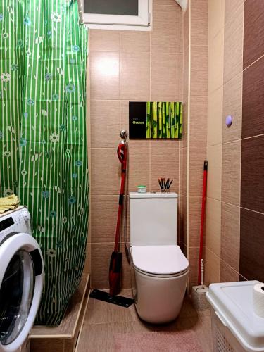 a bathroom with a toilet and a green shower curtain at Apartman Ana in Šabac