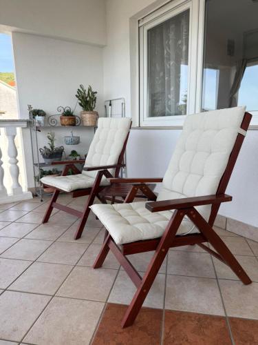 two white chairs sitting on a porch at Apartment Ornik in Crikvenica