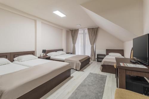 a hotel room with two beds and a flat screen tv at Pensiunea Popasul Ursilor Medve Barlang Peștera Urșilor in Chişcău