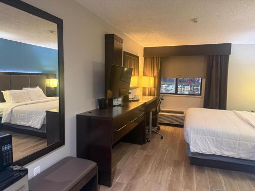 a hotel room with two beds and a desk with a mirror at Quality Inn & Suites Detroit Metro Airport in Romulus