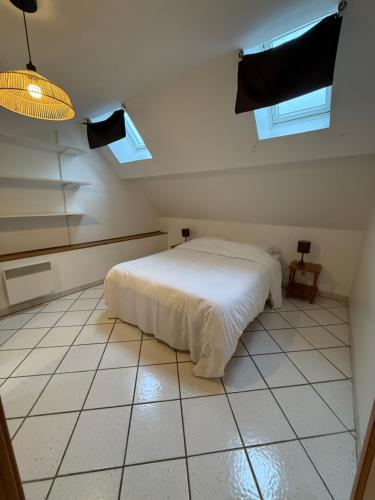 a bedroom with a white bed and two windows at La parenthèse d'Opale in Wissant