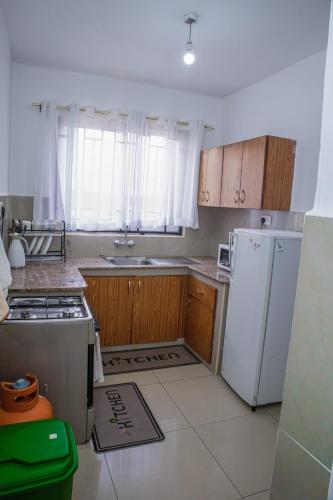 a kitchen with wooden cabinets and a white refrigerator at Chesum's suites in Eldoret
