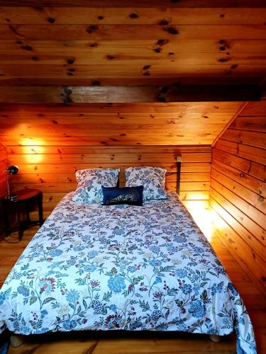 a bedroom with a bed with a blue and white comforter at Chalet à la campagne in Clais