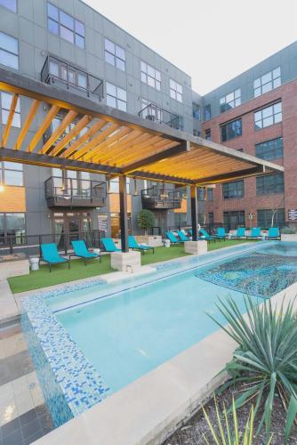 an outdoor swimming pool with blue chairs and a building at Downtown Dallas ELLUM OASIS with Balcony, Pool, Rooftop Deck, Gym, Queen Bed, King Sleeper Sofa, 2 Twin Sleeper Chairs, and Parking Garage in Dallas