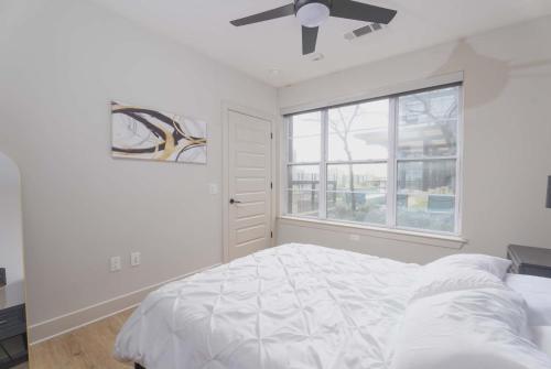 a white bedroom with a bed and a window at Downtown Dallas ELLUM OASIS with Balcony, Pool, Rooftop Deck, Gym, Queen Bed, King Sleeper Sofa, 2 Twin Sleeper Chairs, and Parking Garage in Dallas