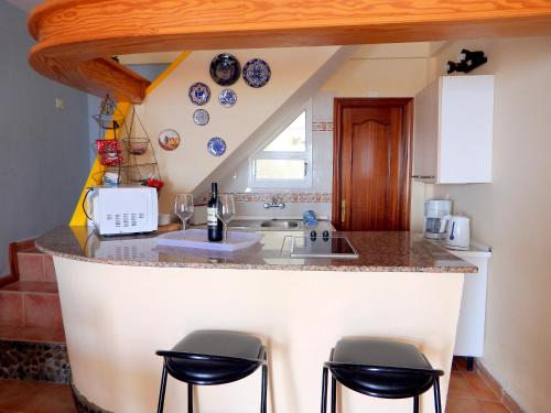 una cocina con encimera con taburetes alrededor en El Varadero, en Igueste