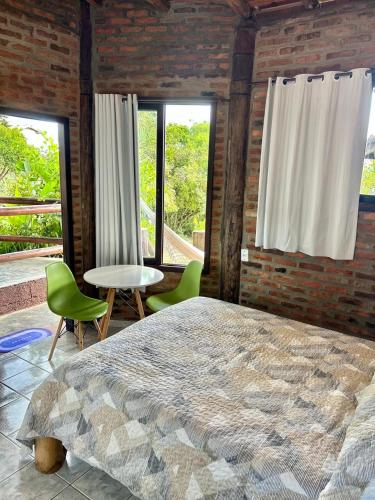 a bedroom with a large bed and chairs and windows at Encanto do Mar Praia do Rosa in Praia do Rosa