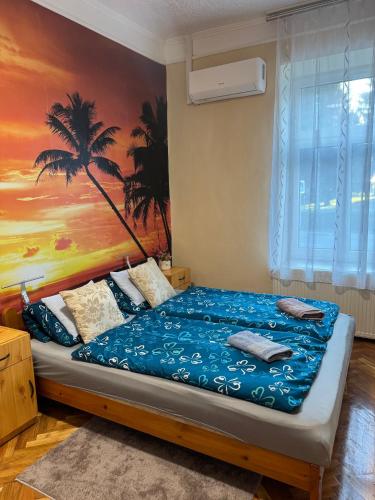 a bedroom with a bed with a palm tree mural at Èlmèny Vendègház in Csurgó