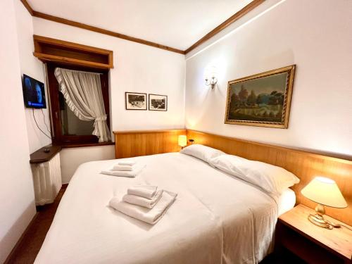 a bedroom with a white bed with two towels on it at Cortina Relax in Cortina dʼAmpezzo