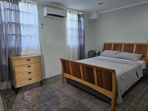 a bedroom with a wooden bed and a dresser and a bed sidx sidx sidx at Modern 1 Bedroom Apartment Near Roseau in Canefield