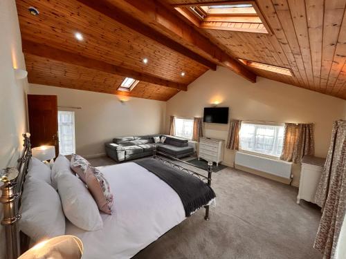a large bedroom with a large bed and a couch at Deandale Stays in Handforth