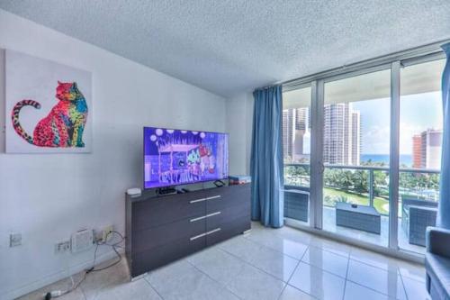 a living room with a tv and a large window at Introdused by Ocean Reserve free parking STR-02559 in Sunny Isles Beach