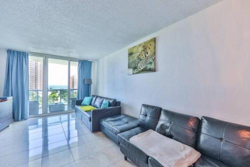a living room with a leather couch and a table at Introdused by Ocean Reserve free parking STR-02559 in Sunny Isles Beach