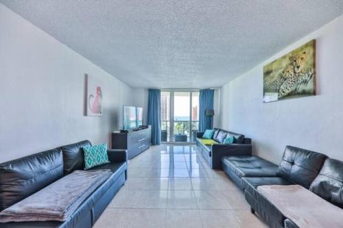a living room with black leather couches and a television at Introdused by Ocean Reserve free parking STR-02559 in Sunny Isles Beach