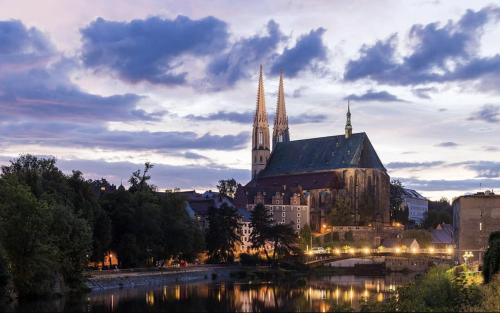 a large church with two towers and a river at An der Neiße in Görlitz