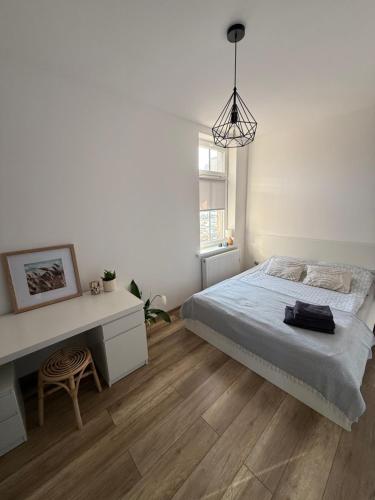 a white bedroom with a bed and a desk at Apartament Nowomiejska in Wałcz