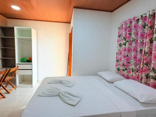 a bedroom with a white bed with towels on it at Flat Studio Casal - Praia da Lagoa do P a u - Coruripe in Coruripe