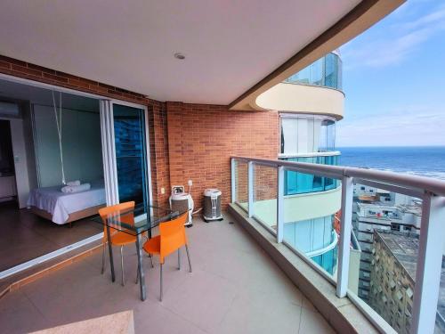a balcony with a table and chairs and the ocean at Book Santos Mar à Vista no Unique Residence 1810 in Santos